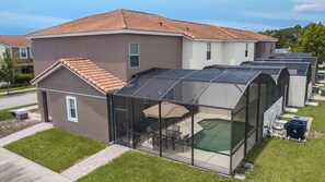 A modern house with a glass-enclosed patio area, a brown exterior, and a tiled roof.