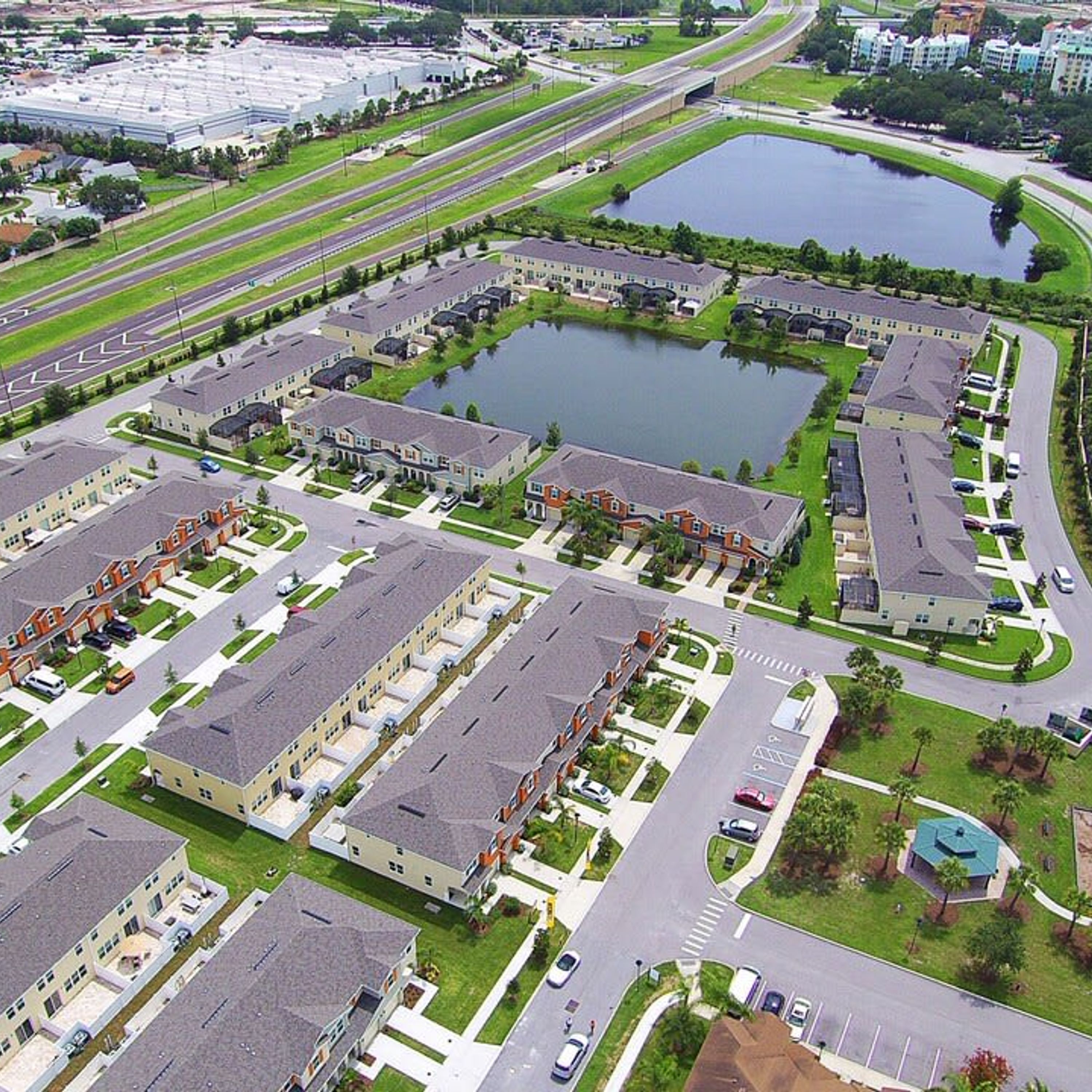 A residential area with multiple apartment buildings, a large parking lot, and a body of water.