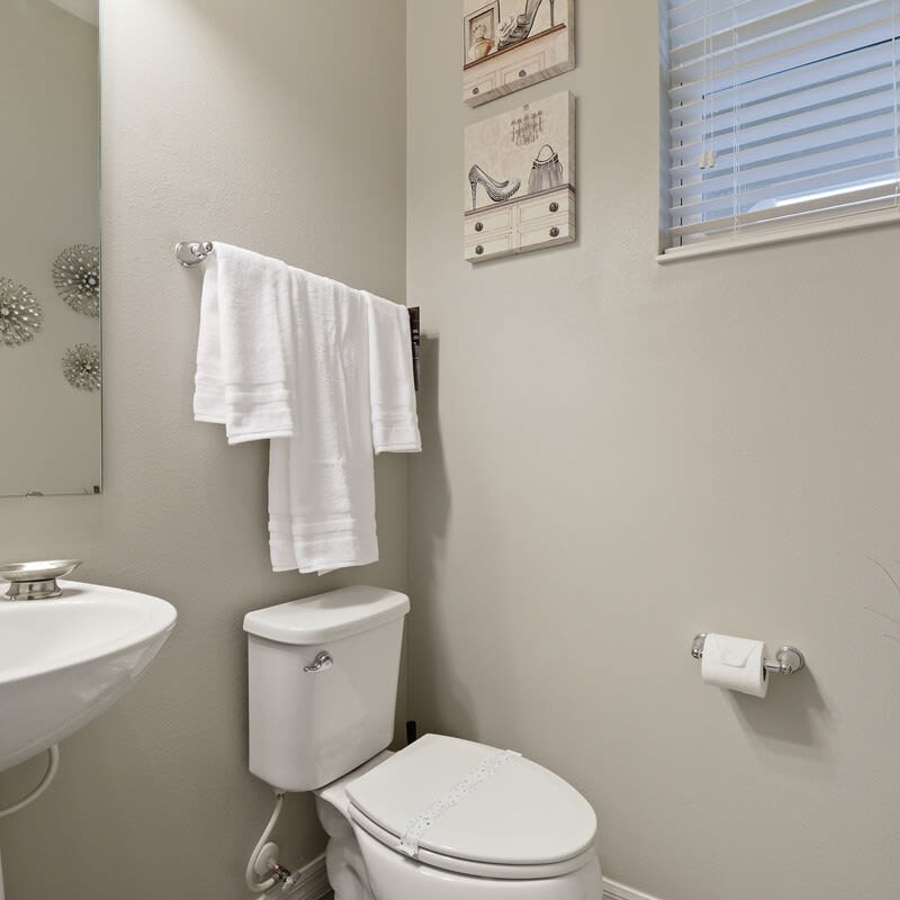 Un baño con inodoro, lavamanos y perchero para toallas.