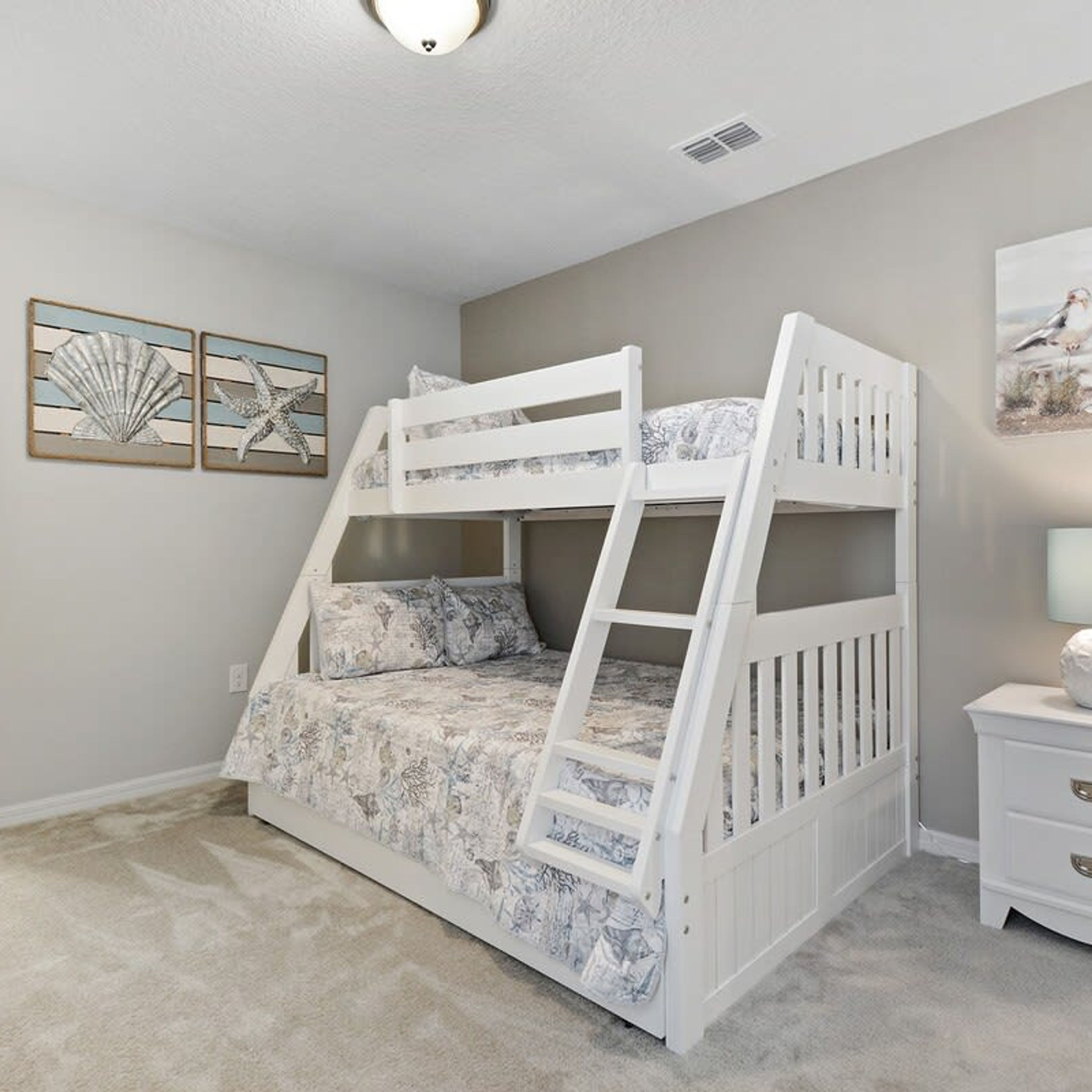 Una cama litera con una escalera, una mesita de noche y dos cuadros en la pared.