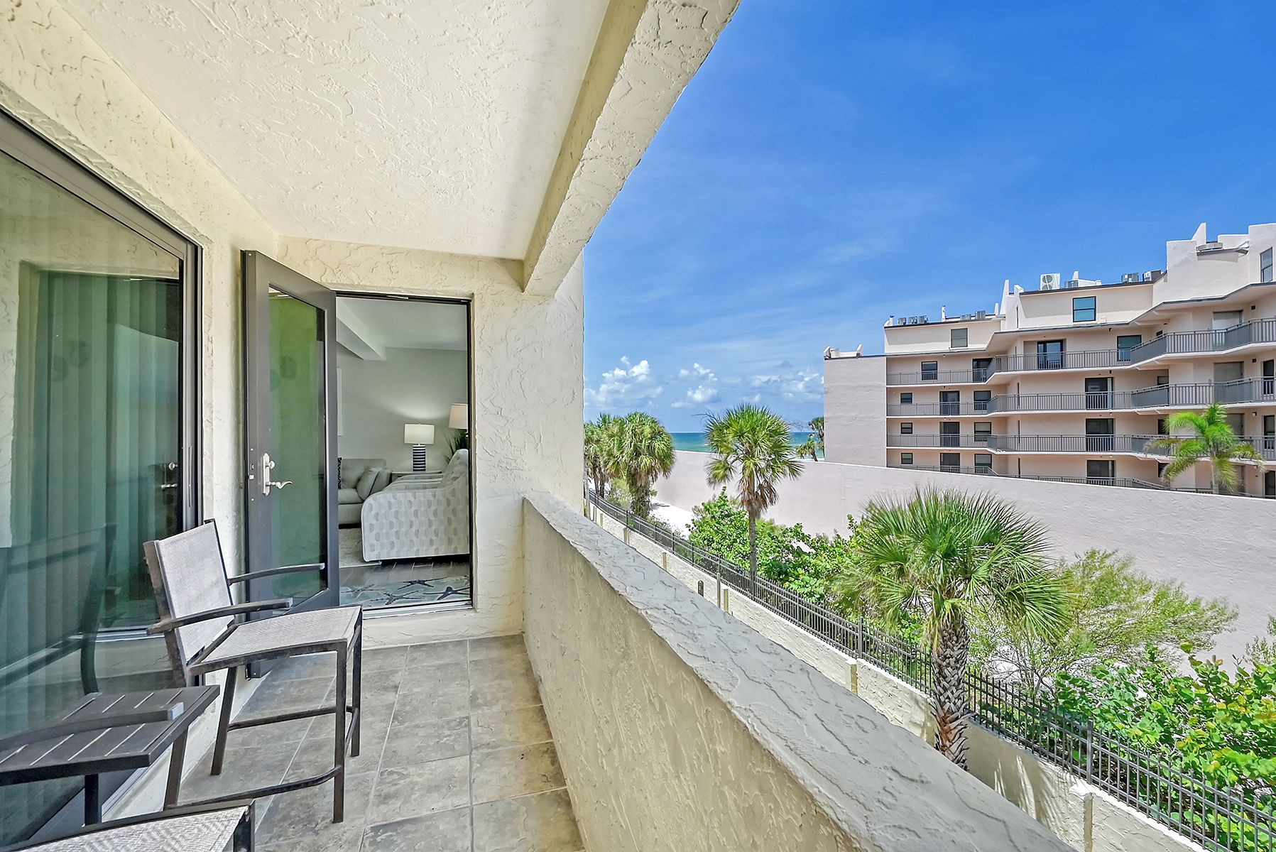 A balcony with a view of a beach and a multi-story building.