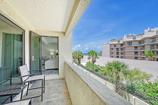 A balcony with a view of a beach and a multi-story building.