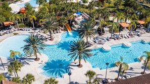 A large outdoor swimming pool with multiple sections, palm trees, and lounge chairs. - Gorgeous 5 Bd w Pool Jacuzzi Close to Disney 6071 (Davenport)