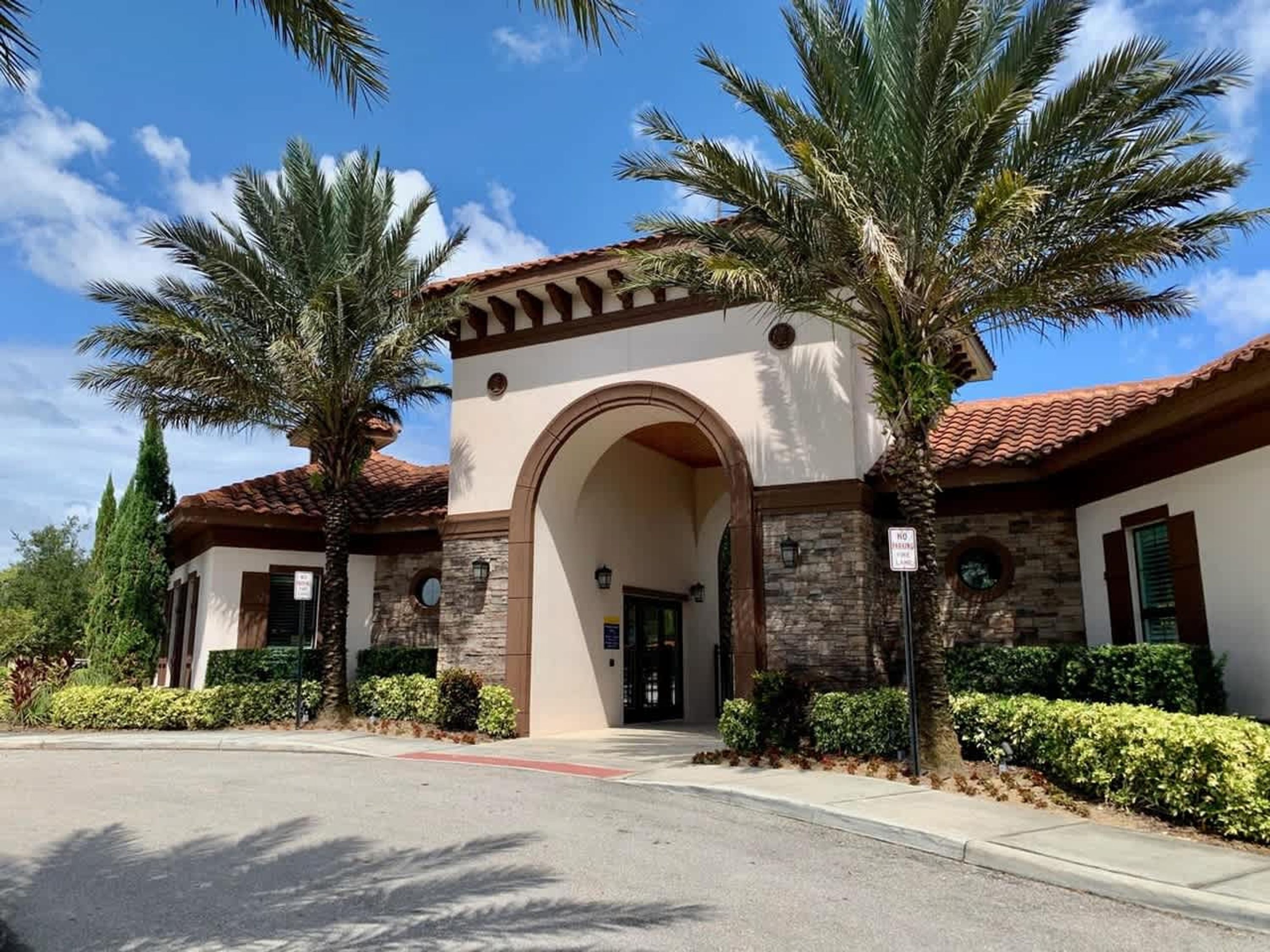 A building with a stone facade, an arched entrance, and palm trees.