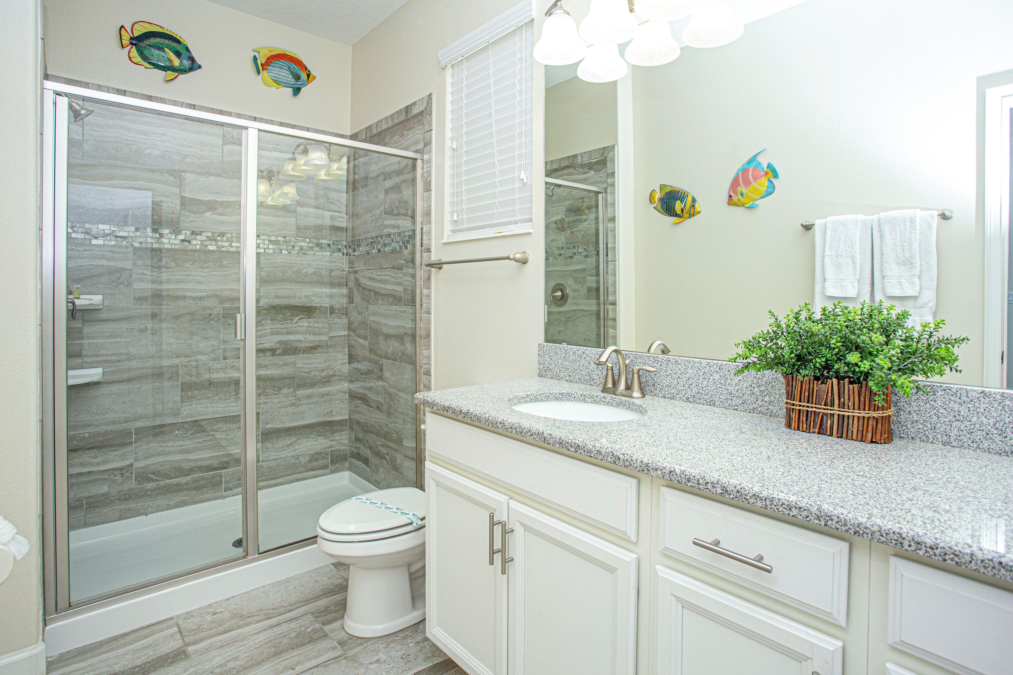 A bathroom with a glass-enclosed shower, a sink, and a toilet.