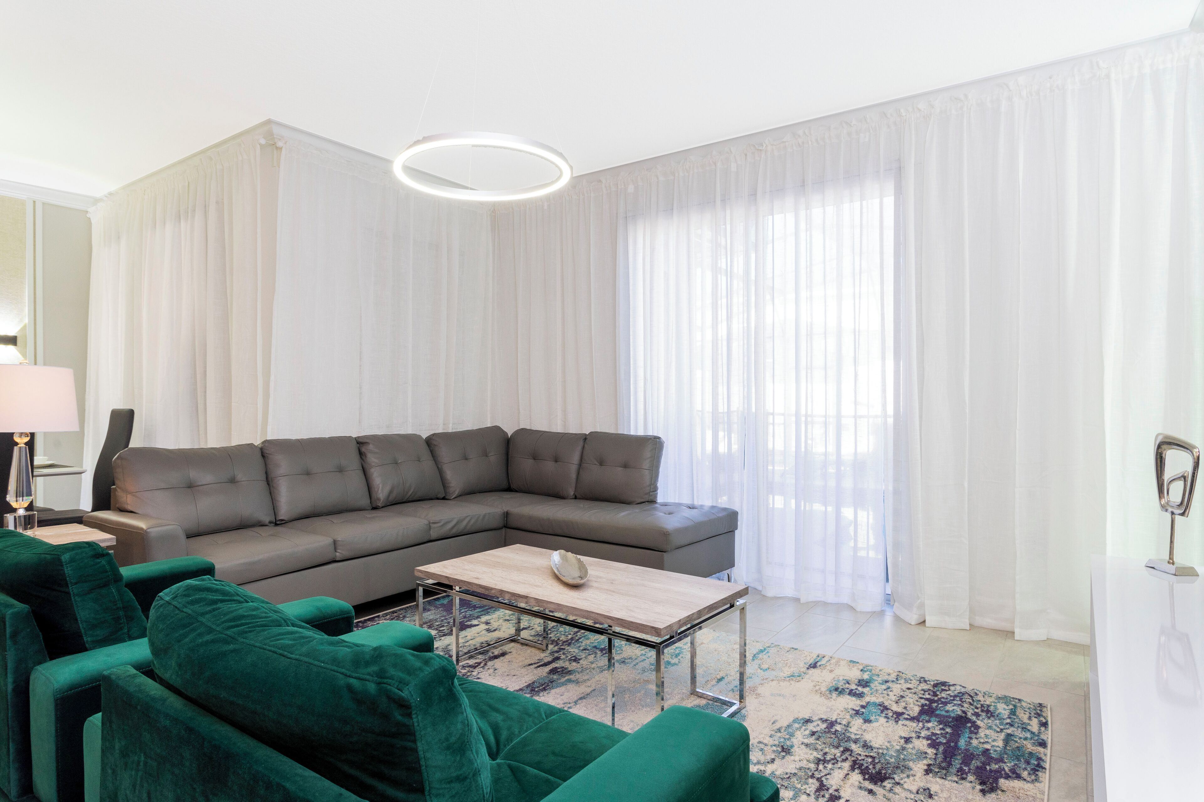 Un salon moderne avec un canapé d’angle, une table basse et un tapis à motifs.