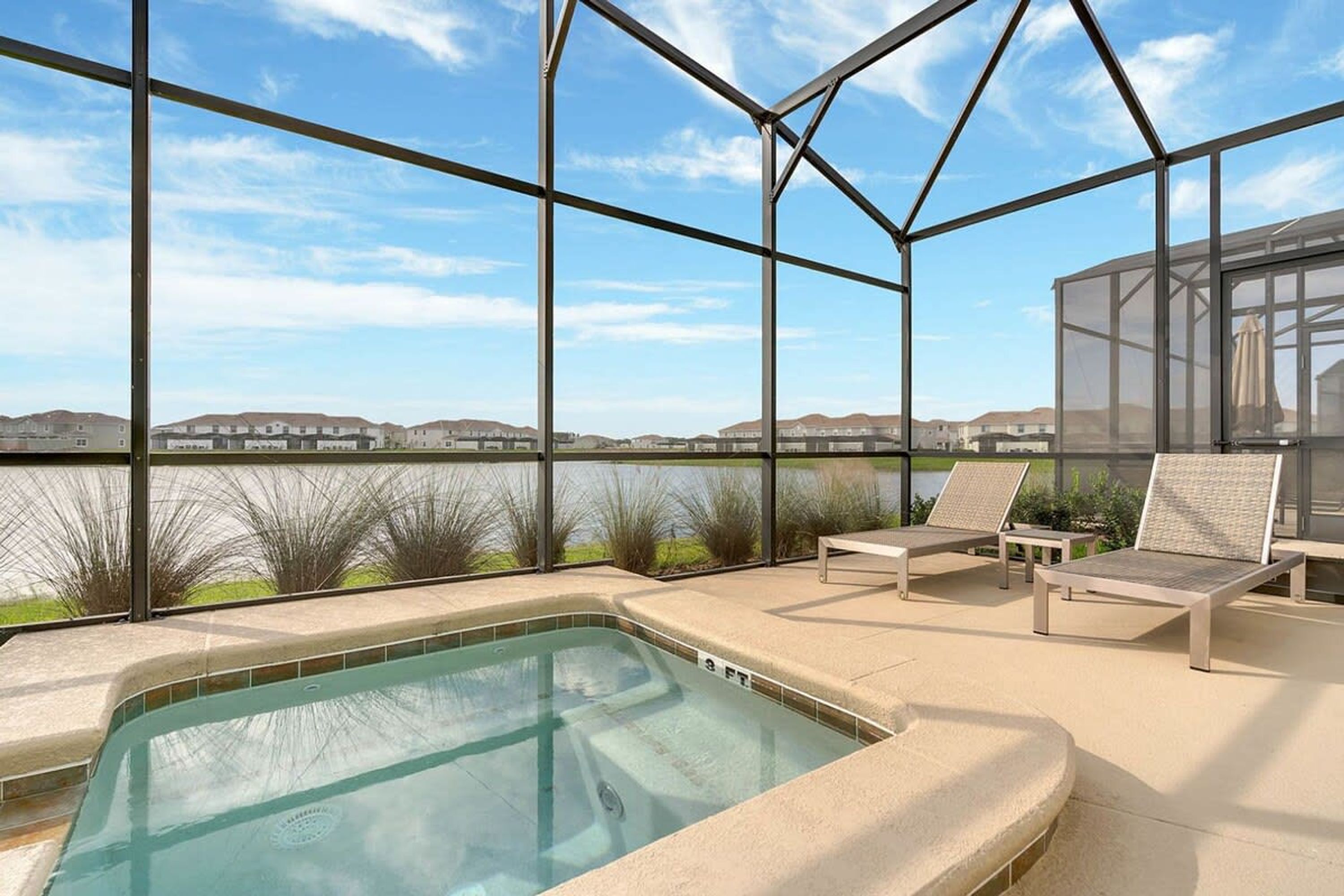 A pool area with a view of a lake and hills, surrounded by a glass enclosure.