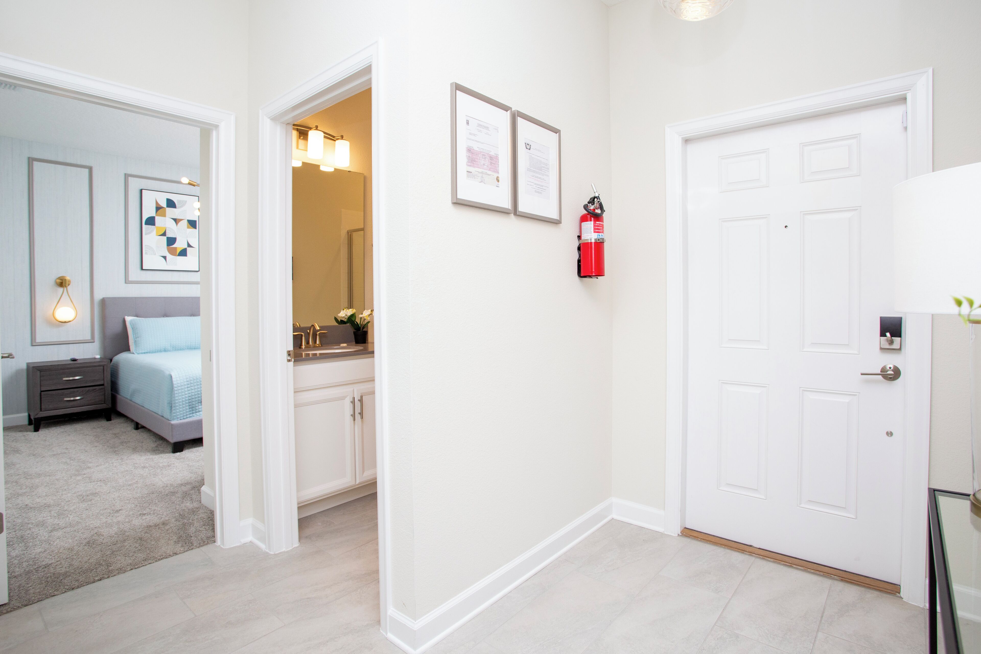 A hotel room with a bed, bedside table, and a bathroom visible through an open door.