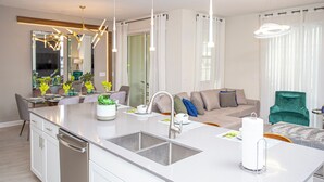 Cozinha moderna com ilha central, eletrodomésticos de aço inoxidável e iluminação pendente.