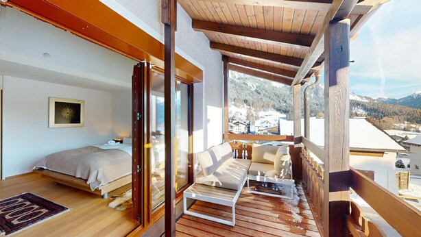 A cozy bedroom with a bed, a bedside table, and a window overlooking a snowy landscape.