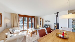 A spacious living room with a sofa set, a wooden dining table, and a fireplace.