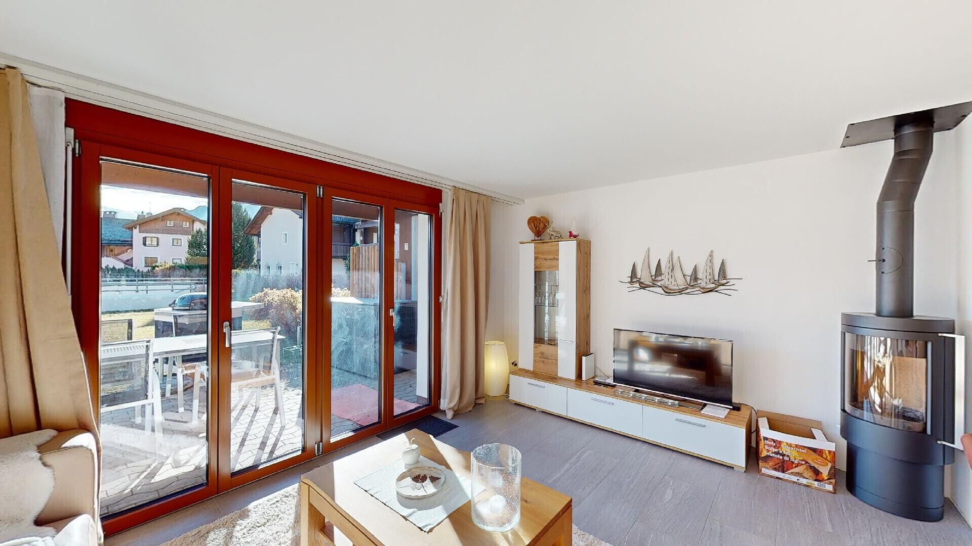 A modern living room with a TV, a fireplace, and a sliding glass door leading to an outdoor area.