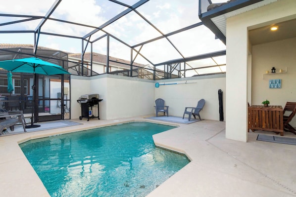 An indoor swimming pool with a glass ceiling, a barbecue area, and seating.