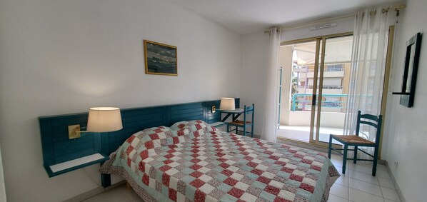 Une chambre à coucher avec un lit, des lampes de chevet, une chaise et un balcon avec vue.