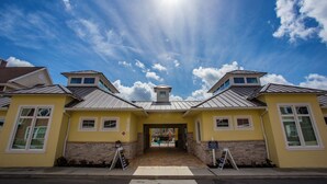 A yellow building with a central entrance, stone base, and metal roof. - Gorgeous 4 Bedroom Family Friendly Close to Disney 7573 (Kissimmee)