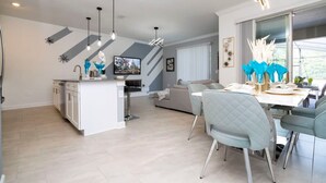 Una cocina moderna con una isla central, comedor con sillas y zona de estar con sofá.
