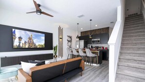 A modern living room with a sofa, TV, and dining area.