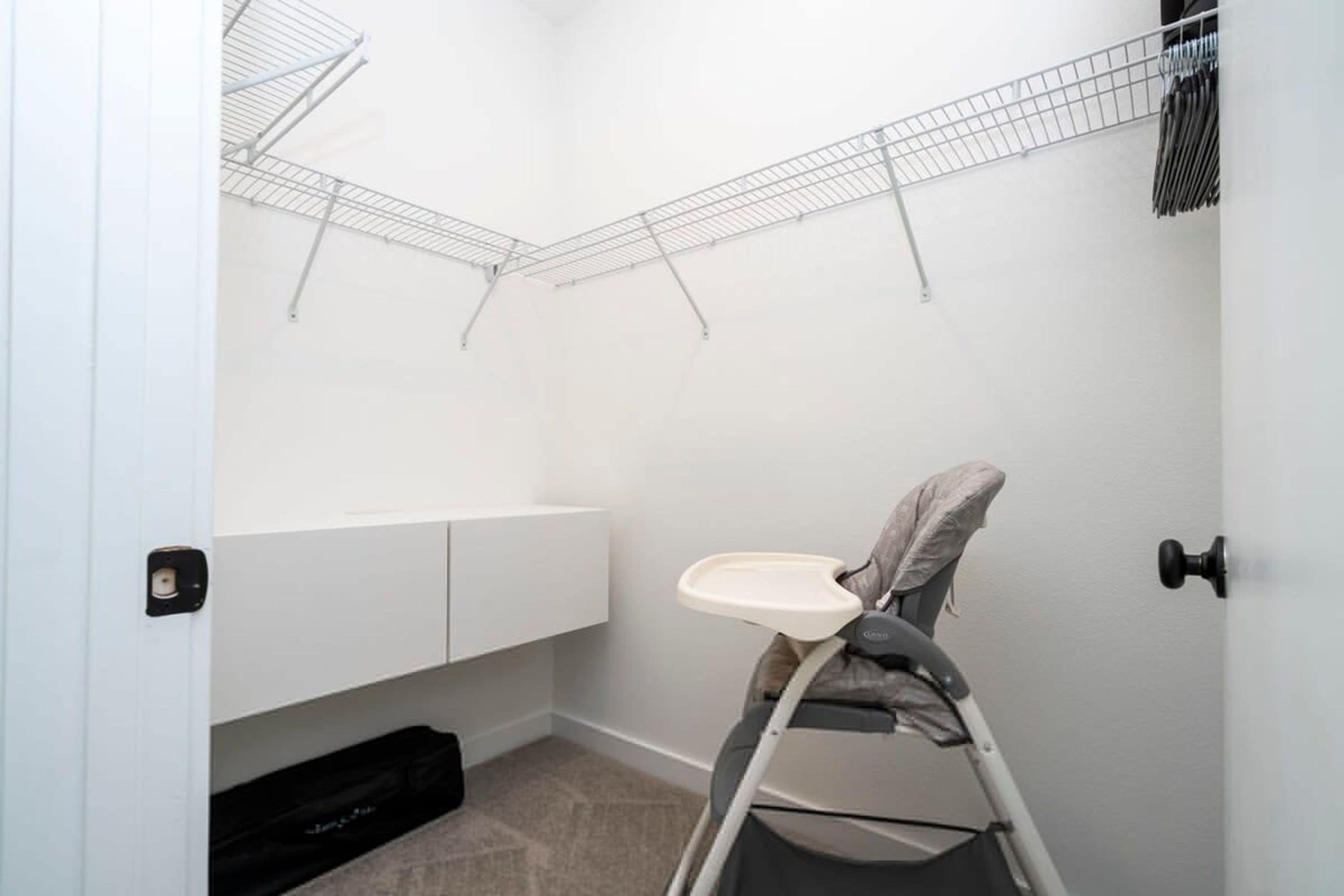 A corner room with a baby stroller, a white cabinet, and a wire shelf.