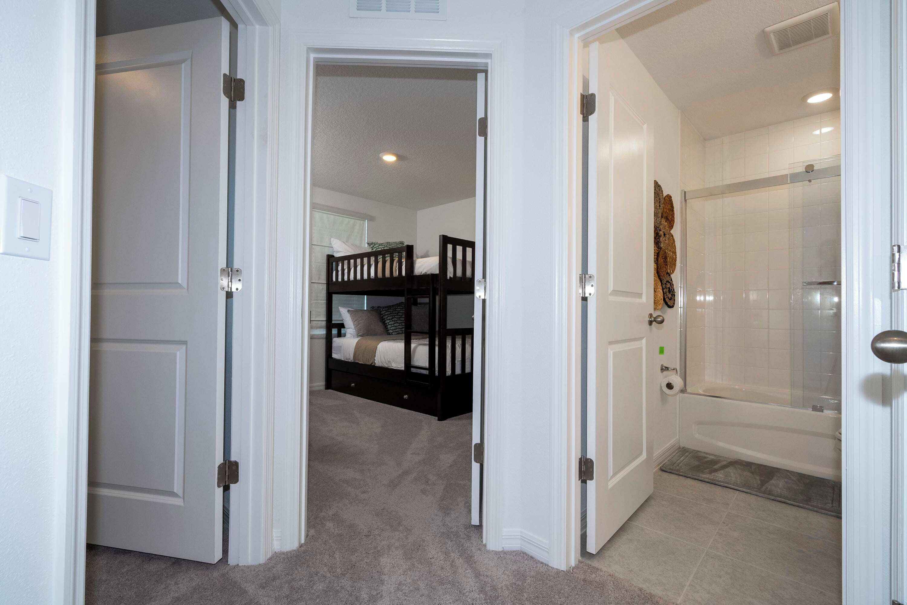A bedroom with a bunk bed and a bathroom with a bathtub.