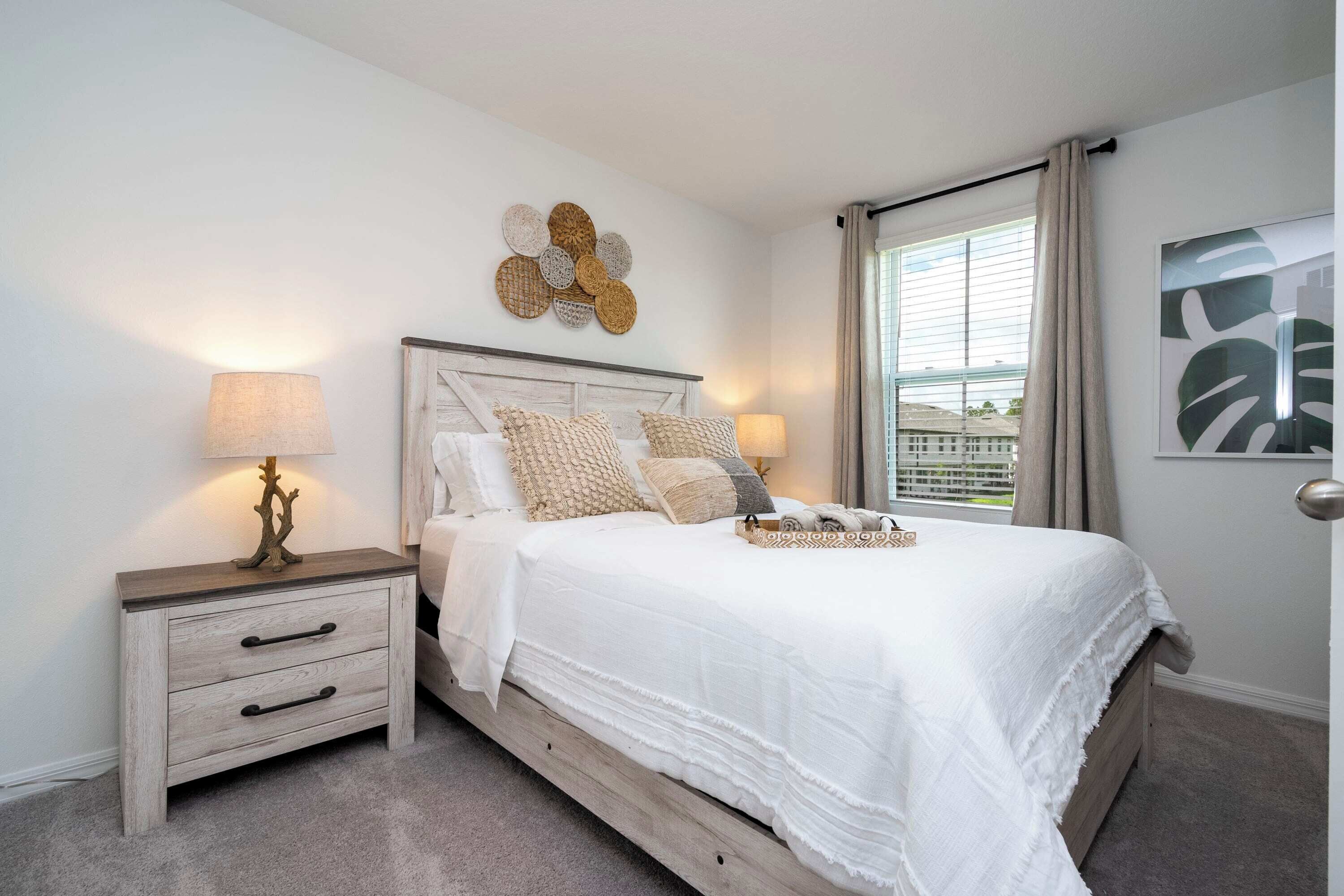 A bedroom with a bed, bedside tables, and a window with curtains.