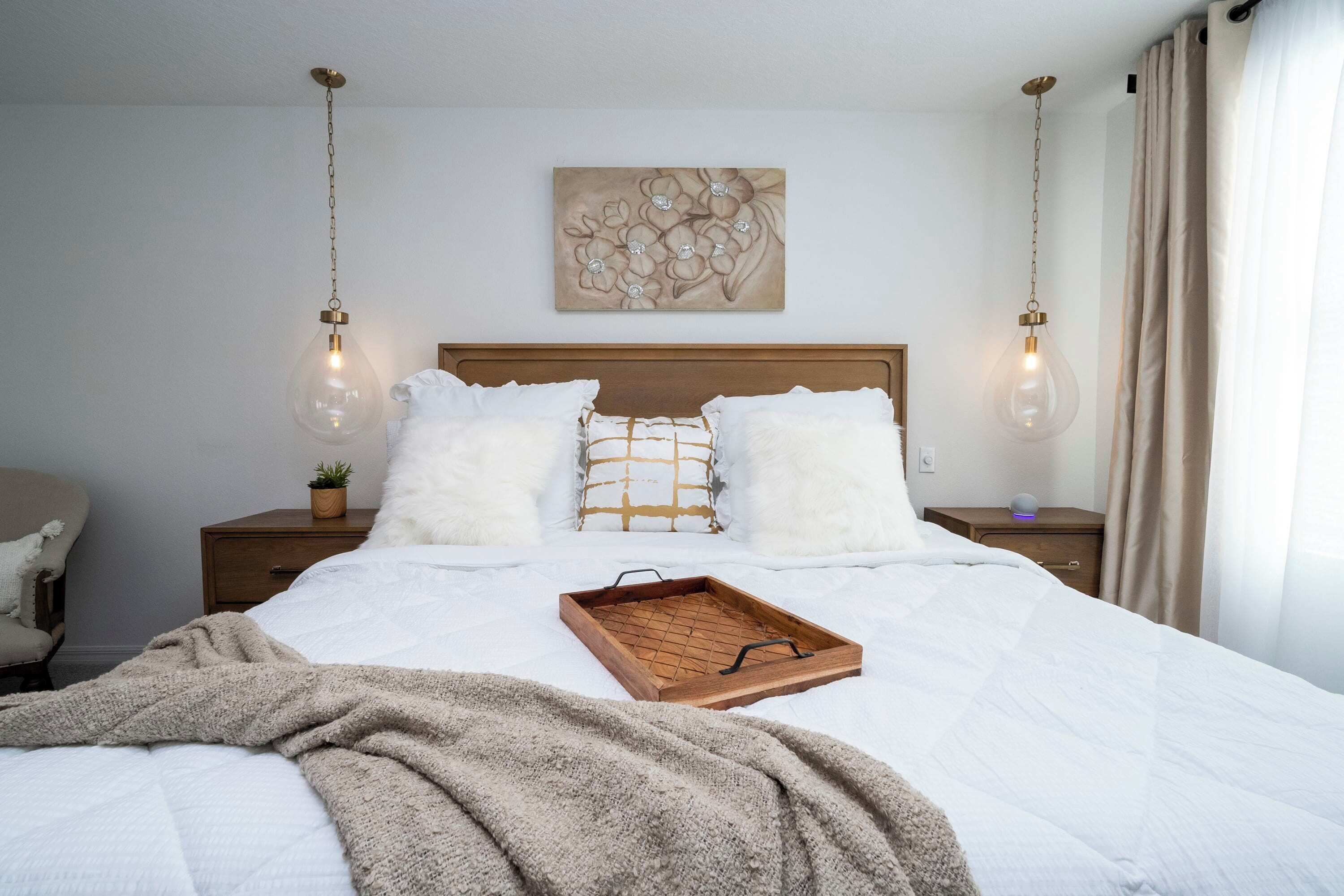A neatly made bed with a wooden headboard, a decorative wall piece above, and a bedside table with a lamp.