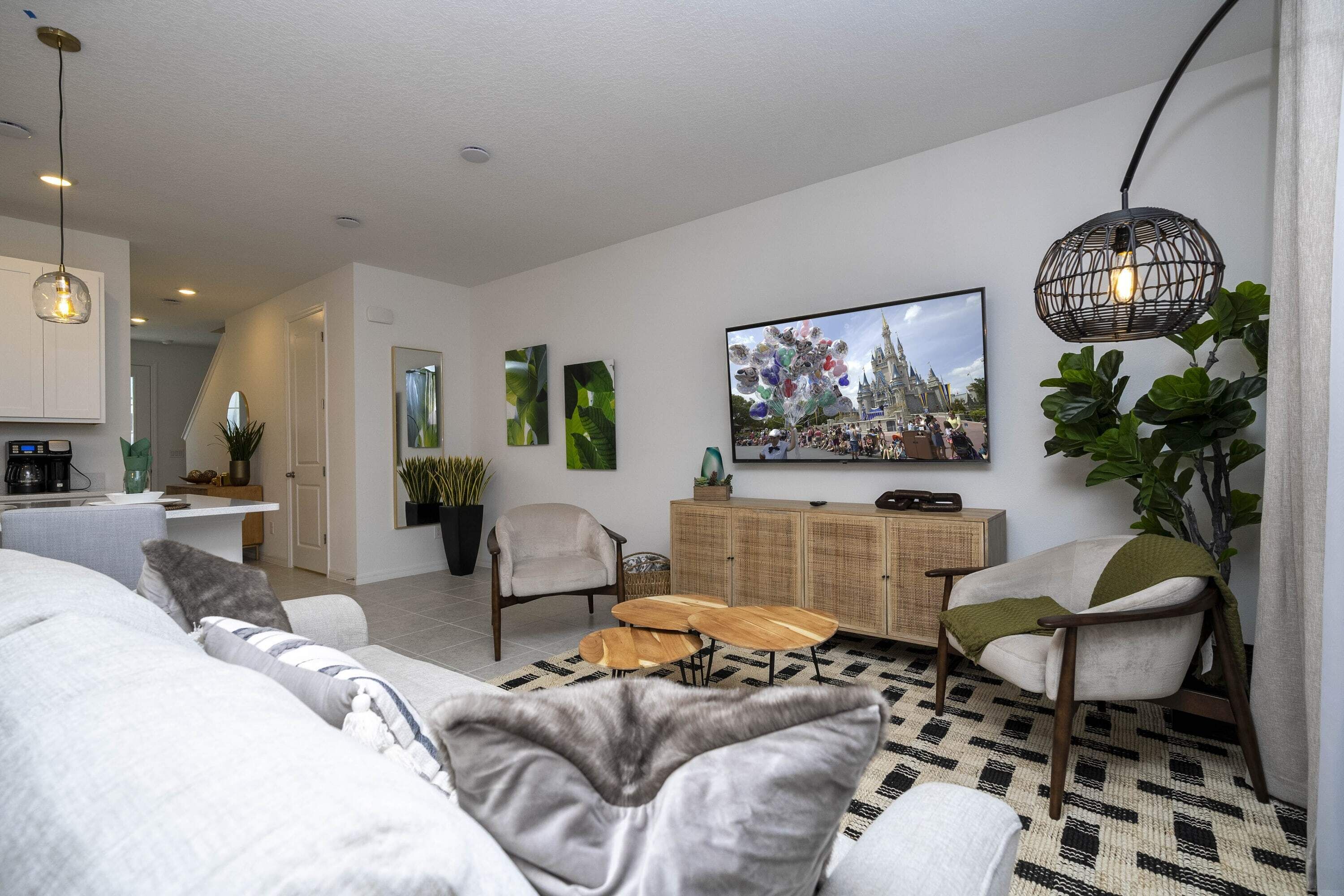 A modern living room with a sofa, armchairs, a coffee table, and a TV mounted on the wall.