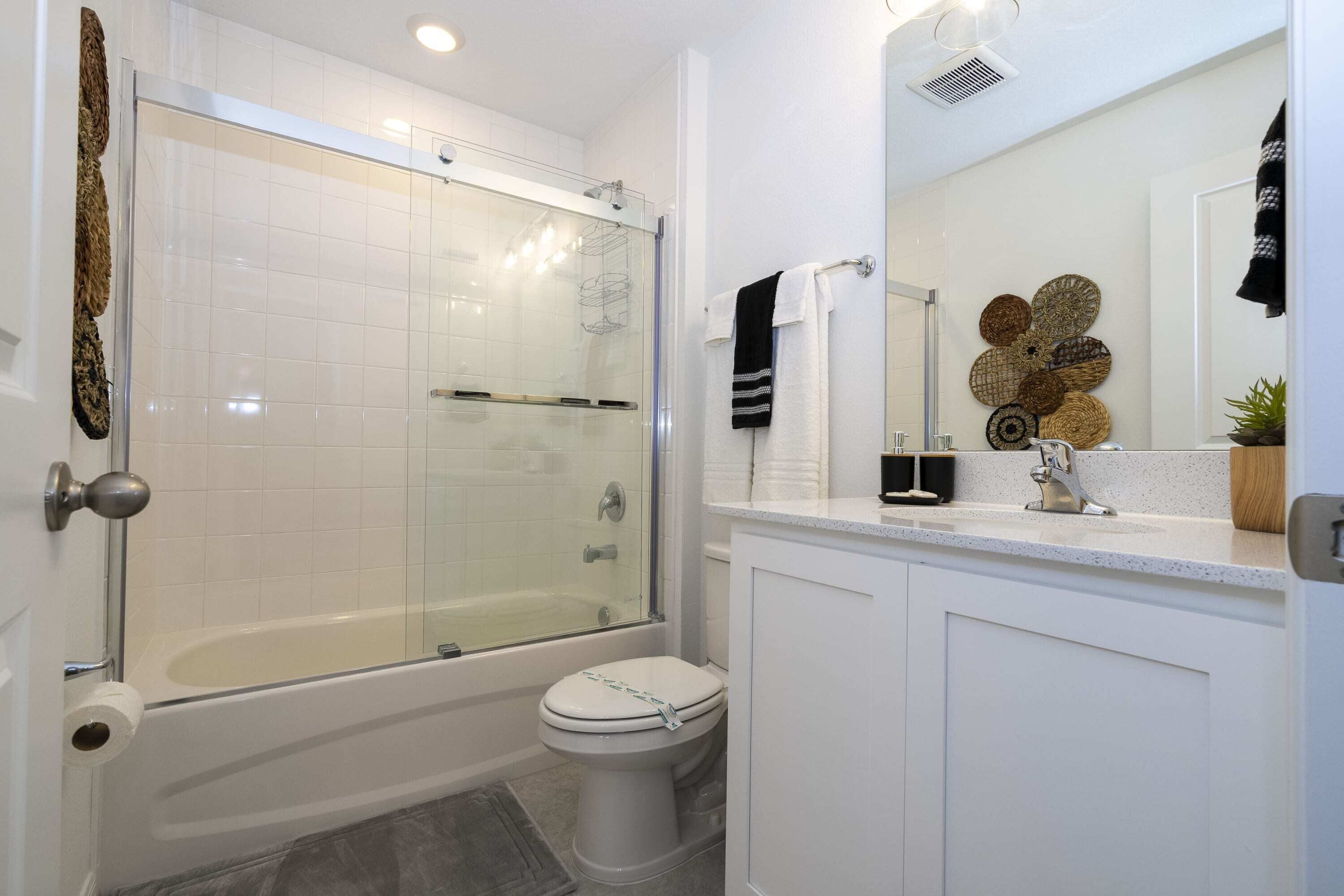 A modern bathroom with a glass-enclosed shower, a toilet, and a sink with a mirror above it.