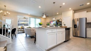 Une cuisine moderne avec des meubles blancs, des appareils électroménagers en acier inoxydable et un îlot central.