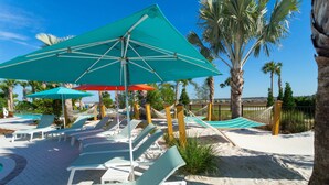 Un espace aménagé sur la plage, avec des chaises longues, des parasols et un hamac.