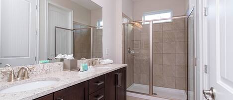A modern bathroom with two sinks, a large mirror, and a glass-enclosed shower.