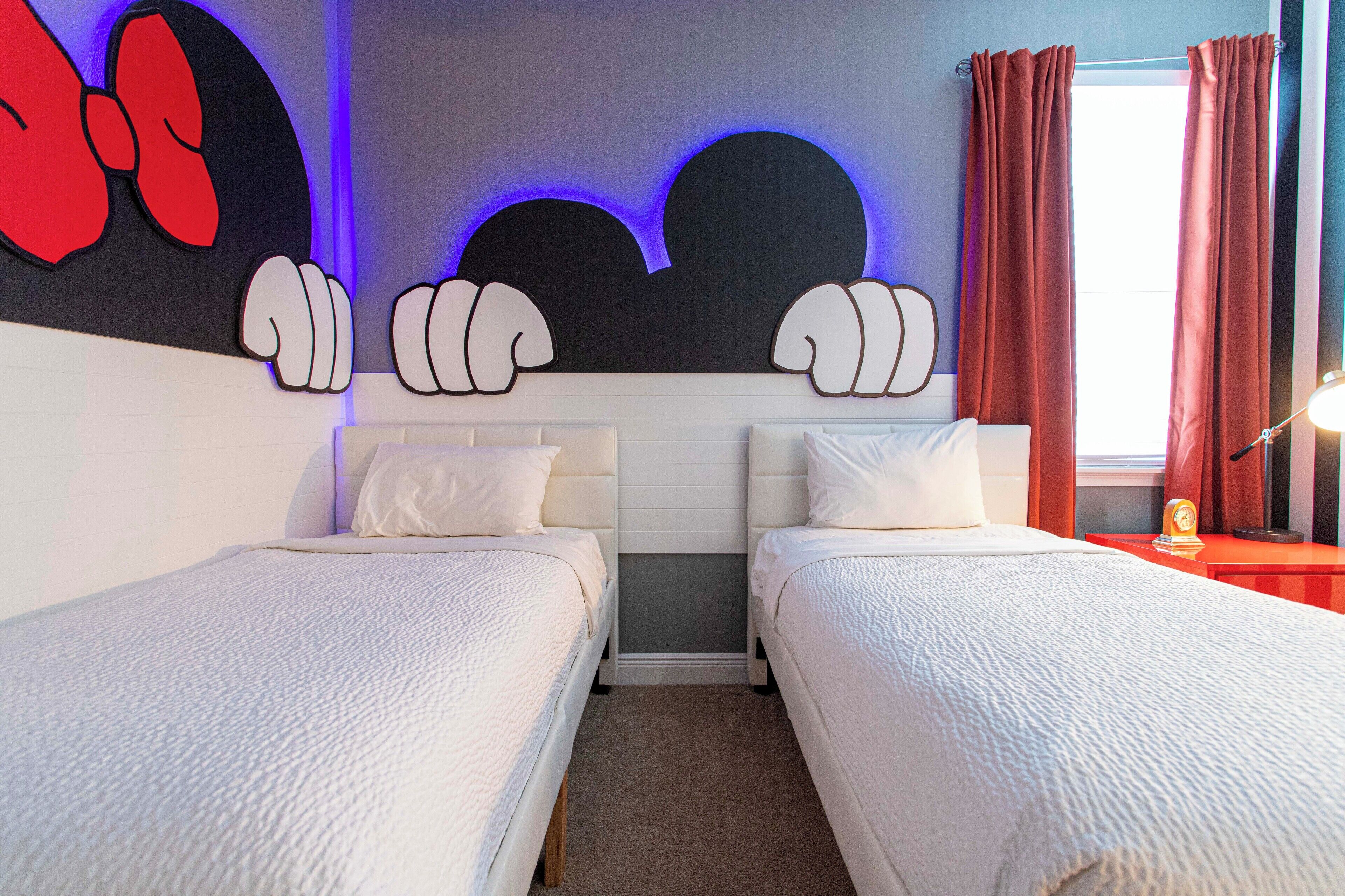 A hotel room with two beds, a large wall art piece, and a window with curtains.