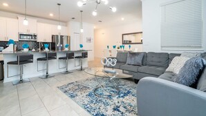 Une cuisine moderne avec des meubles blancs, des appareils en acier inoxydable et un coin bar équipé de tabourets.