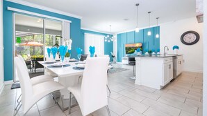 Une cuisine moderne avec des meubles blancs, un îlot central et des luminaires suspendus.