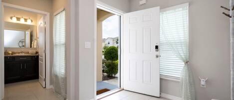 A hallway leading to a door with a view of a garden.