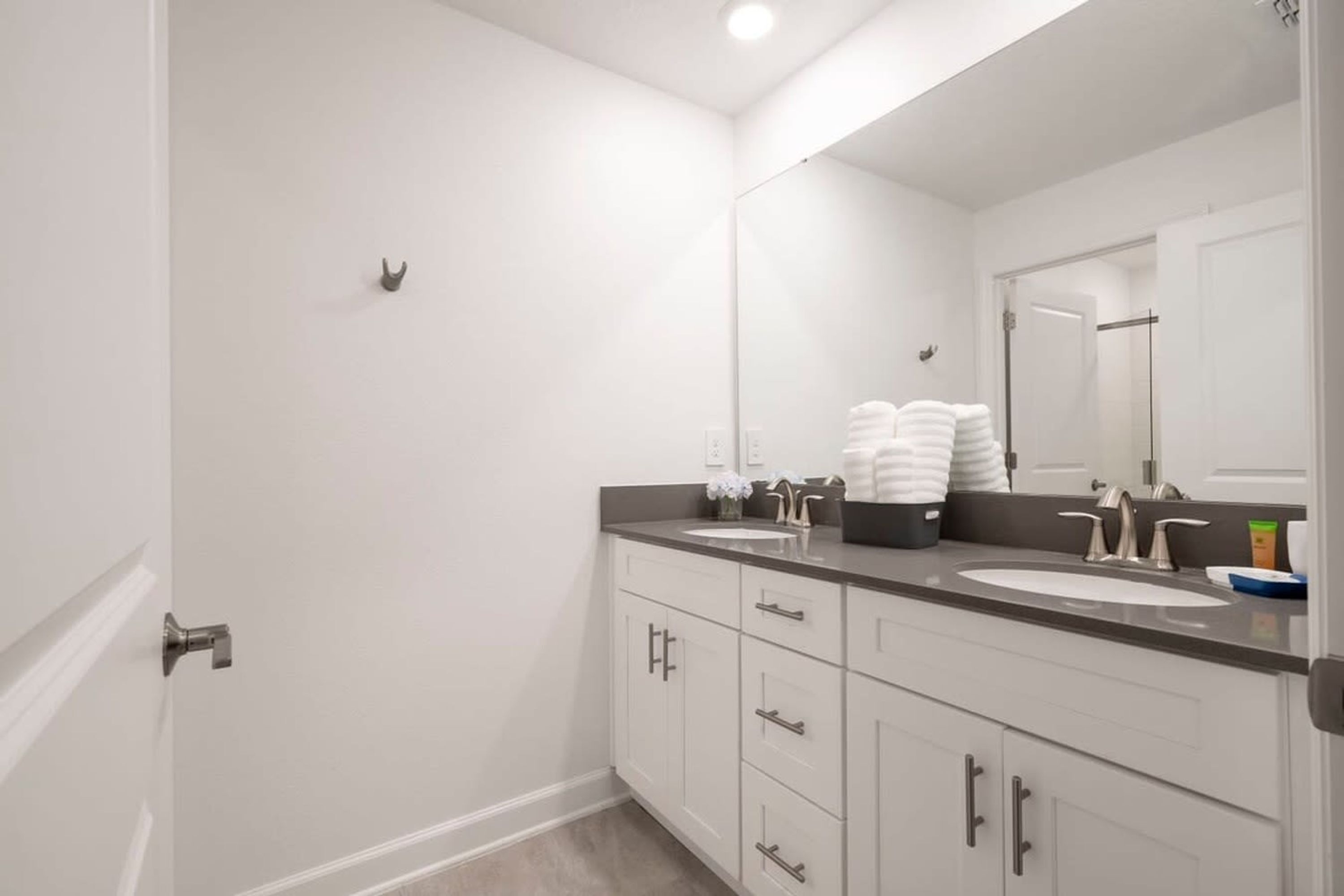 A bathroom with two sinks, a large mirror, and a shower area.