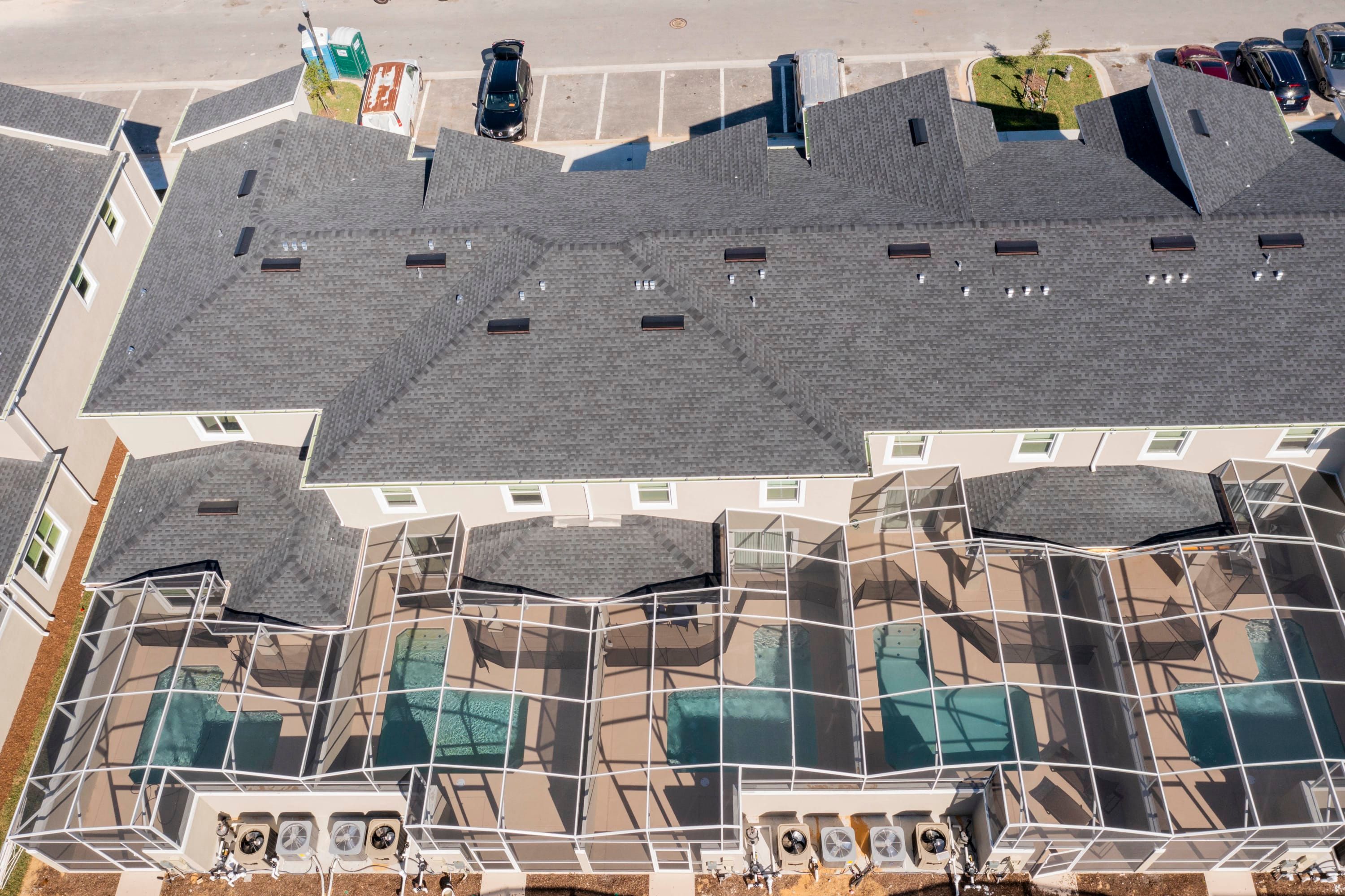 A multi-story building with a distinctive roof structure, multiple windows, and a swimming pool area with a glass enclosure.