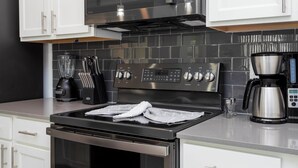 Een moderne keuken met roestvrijstalen apparatuur, waaronder een fornuis, magnetron en koffiezetapparaat.