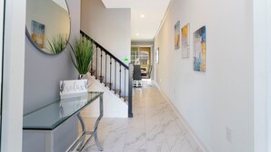A hallway with a glass table, a mirror, and a staircase. - Stunning 4 Bd w Pool Close to Disney Champions Gate 990 (Davenport)