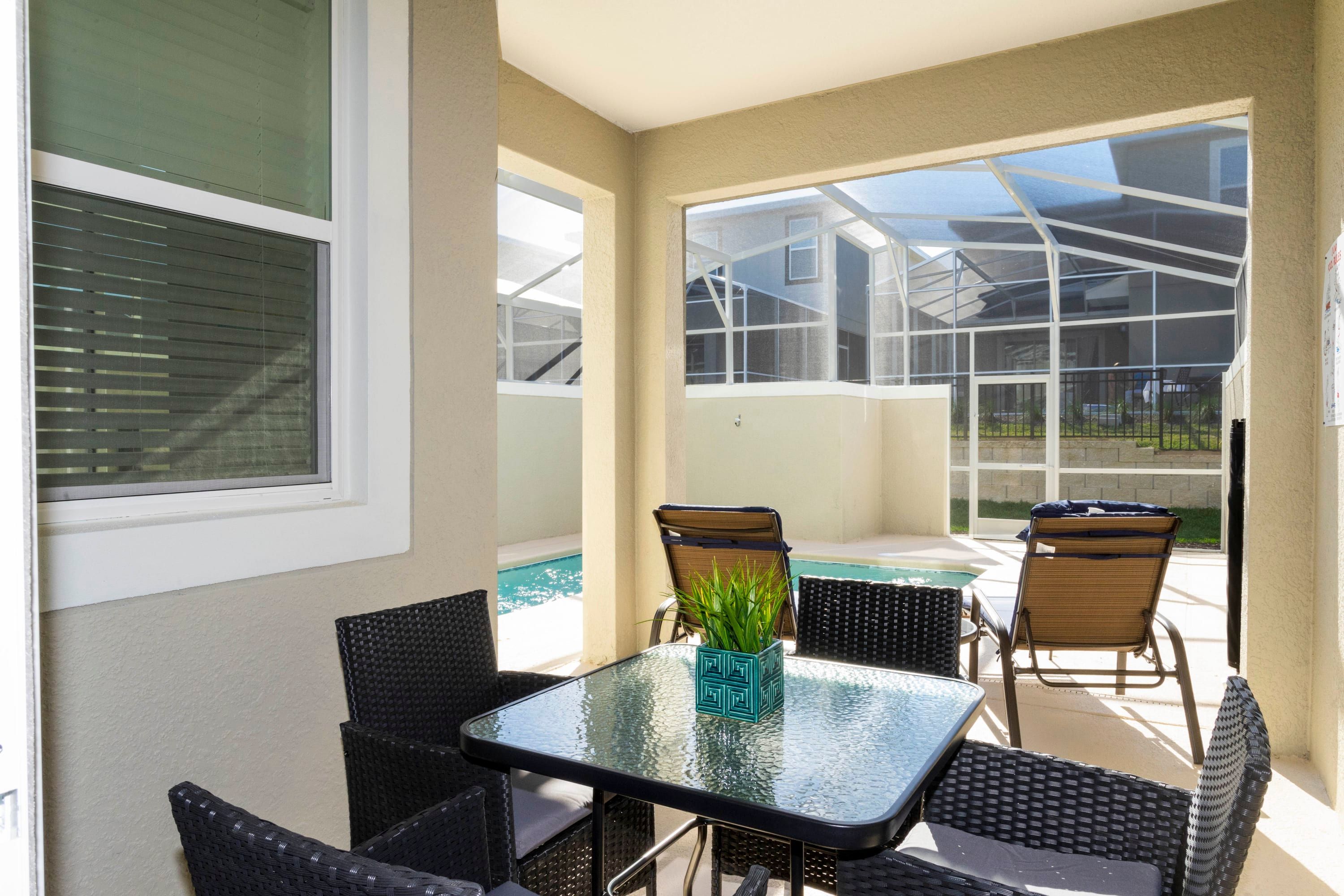 A patio with a glass table, wicker chairs, and a potted plant.