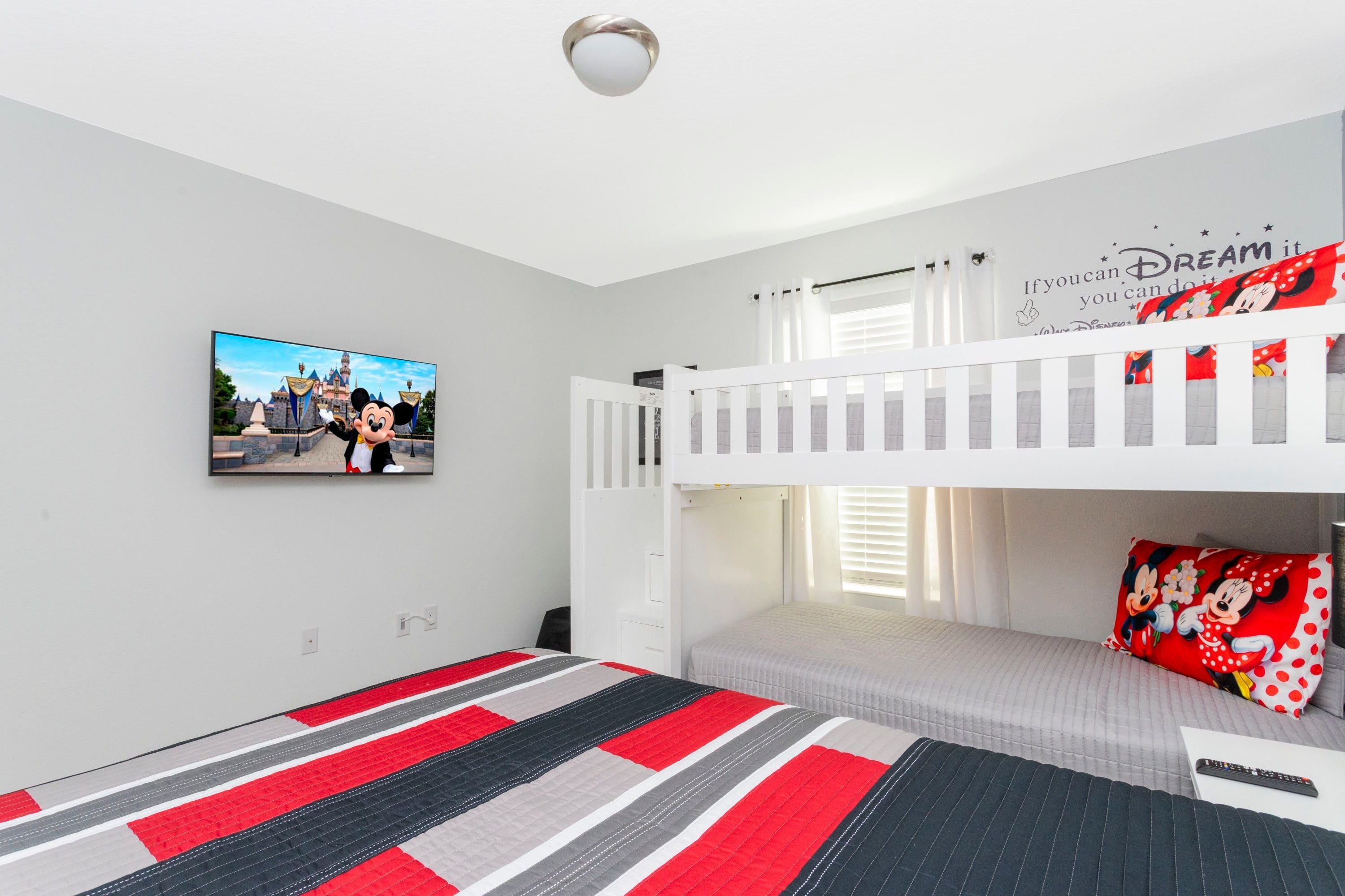 Ein Schlafzimmer mit Etagenbett, einem Flachbildfernseher an der Wand und einem motivierenden Poster.