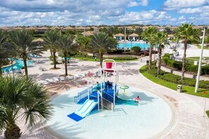 A water park with a slide, a pool, and palm trees. - Stunning 4 Bd w Pool Close to Disney Champions Gate 990 (Davenport)