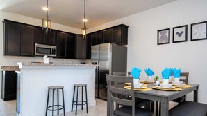 A modern kitchen with dark cabinets, stainless steel appliances, and a central island with bar stools. - Splendid 4Bd Close to Disney Holly Village 132 (Davenport)