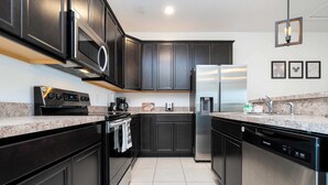 A modern kitchen with dark cabinetry, stainless steel appliances, and granite countertops. - Splendid 4Bd Close to Disney Holly Village 132 (Davenport)