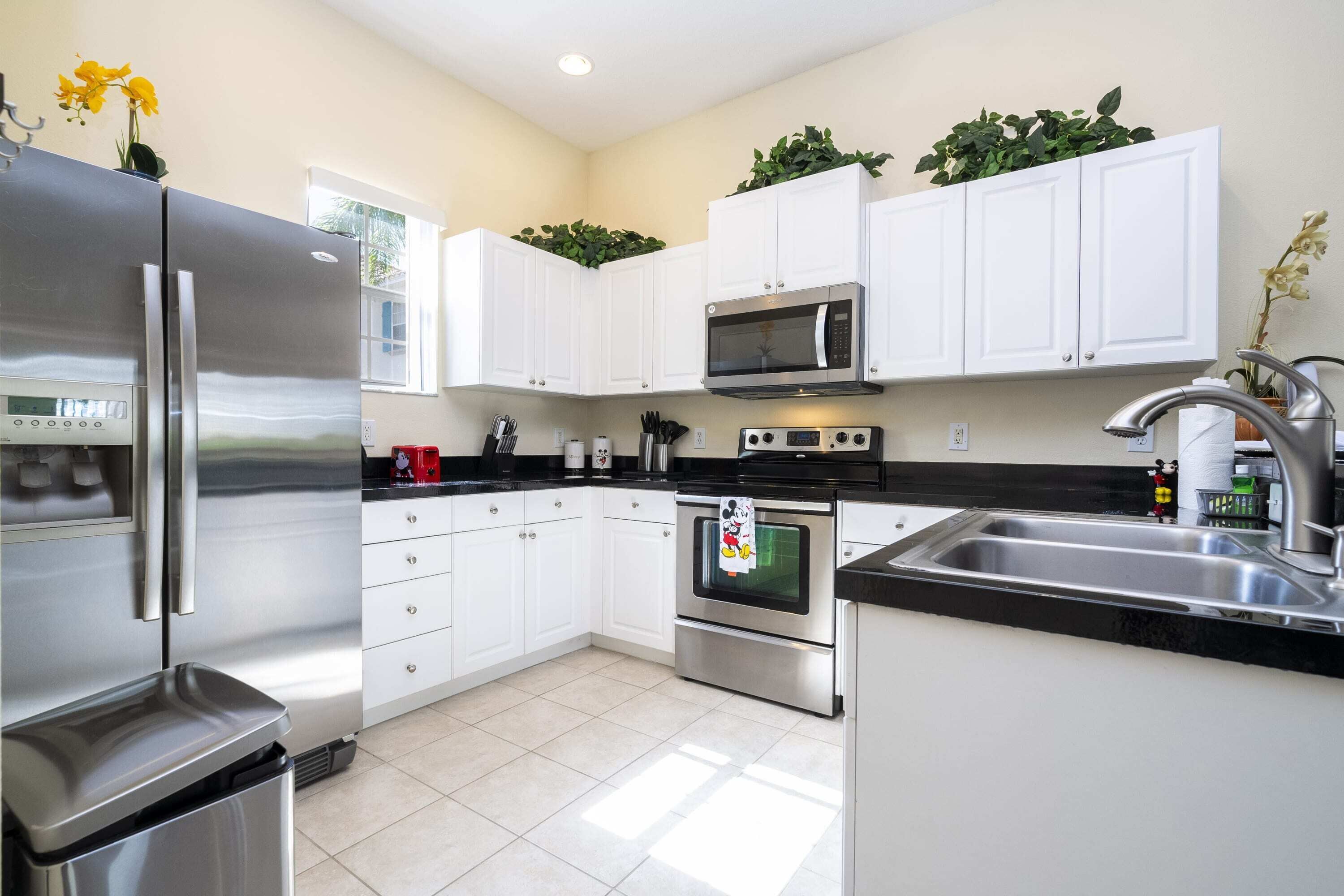 A modern kitchen with white cabinets, stainless steel appliances, and a black countertop.