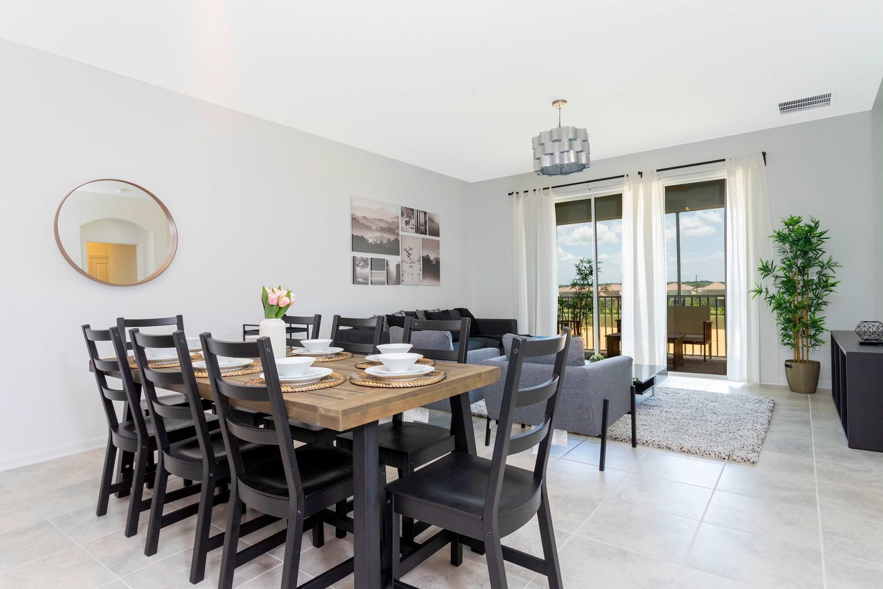 A dining area with a wooden table and chairs, a large mirror, and a sofa.
