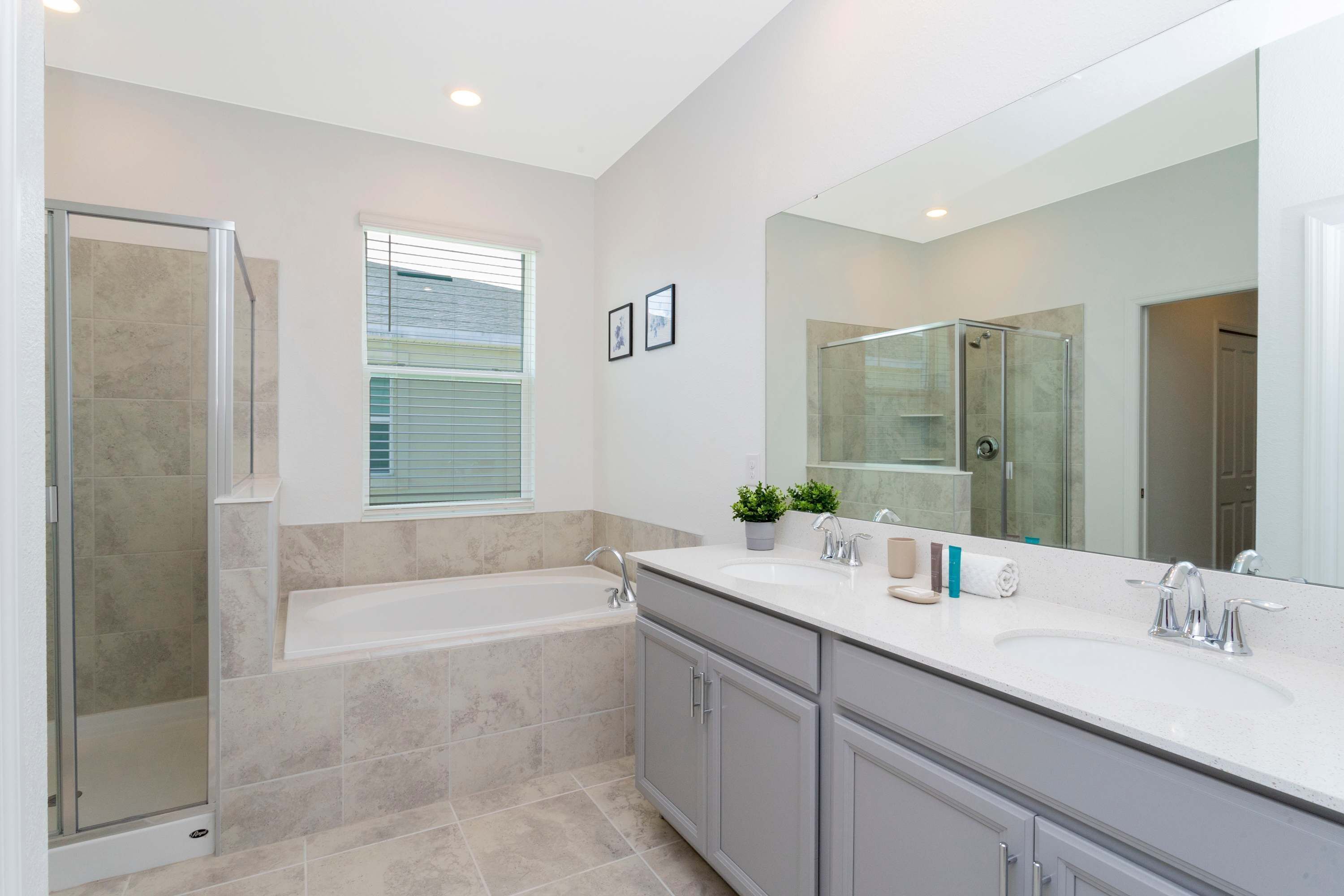 A modern bathroom with a bathtub, shower, vanity, and a large mirror.