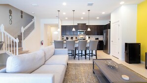 A modern kitchen with dark cabinets, a central island, and pendant lighting. - Splendid 5 Bd w Screened Pateo Pool Windsor Westside 8921 (Kissimmee)