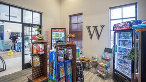 A hotel lobby with a reception desk, vending machines, and a display of colorful towels. - Splendid 5 Bd w Screened Pateo Pool Windsor Westside 8921 (Kissimmee)