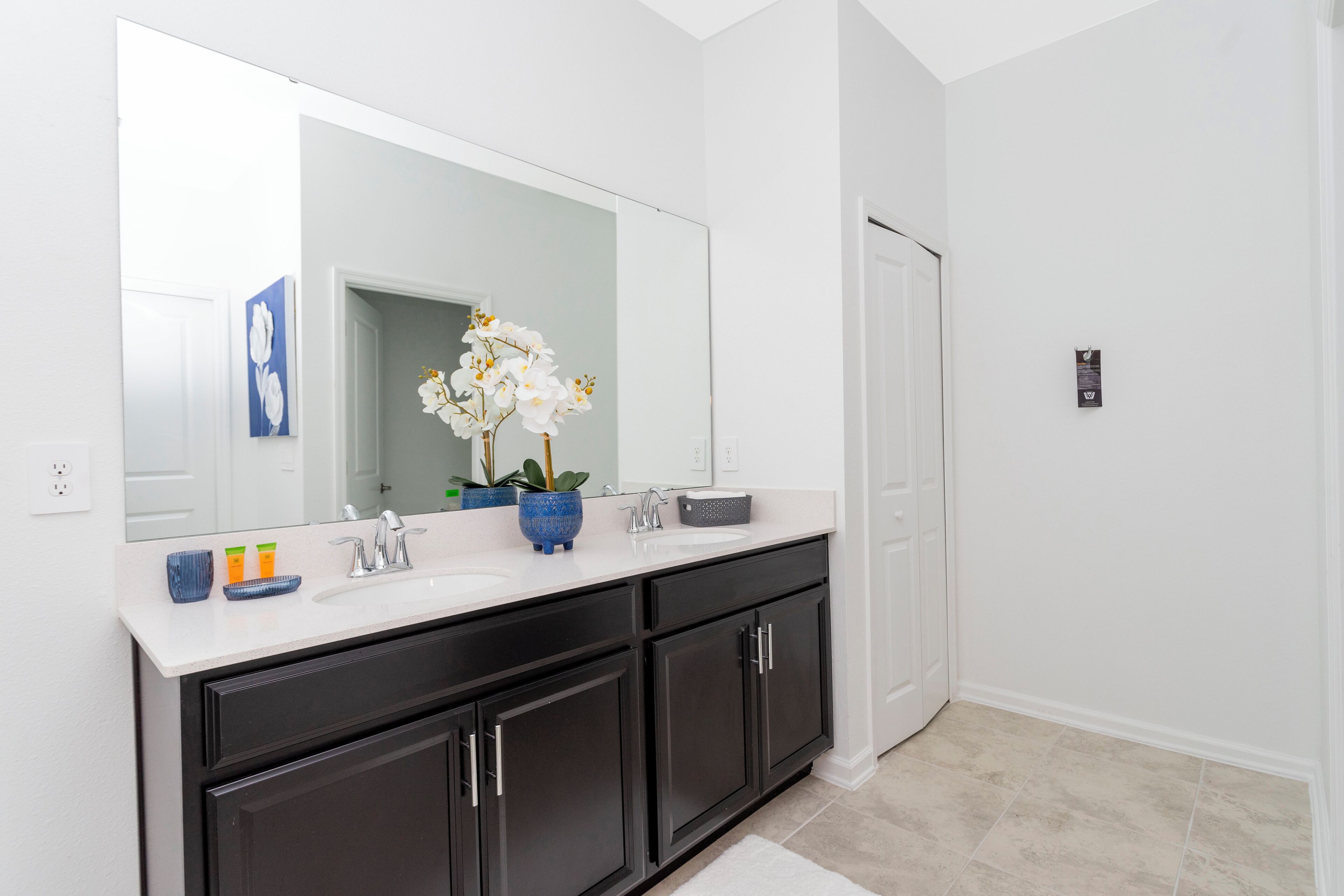 A modern bathroom with a white vanity, black cabinets, and a large mirror.