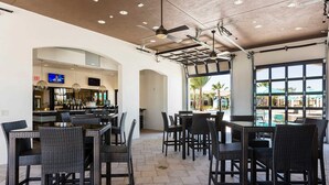 Restaurante con terraza, ventiladores de techo y vista al área de la piscina.